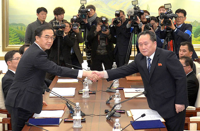 Cho Myoung-Gyon (left), the South Korean minister of unification, and Ri Son Gwon, chairman of the North Korean Committee for the Peaceful Reunification of the Fatherland, shake hands across the table at the Peace House in the Panmunjom truce village on Jan. 9. (Yonhap News)