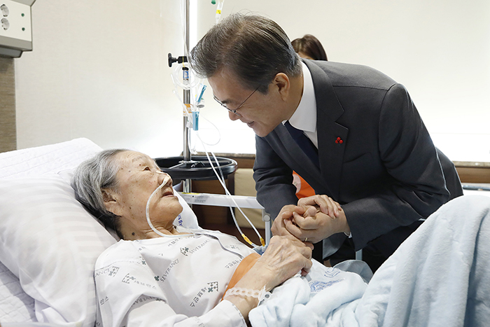 President Moon Jae-in (right) visits Kim Bok-dong, a survivor of colonial and wartime sexual slavery, currently hospitalized at Severance Hospital, in Seoul on Jan. 4.