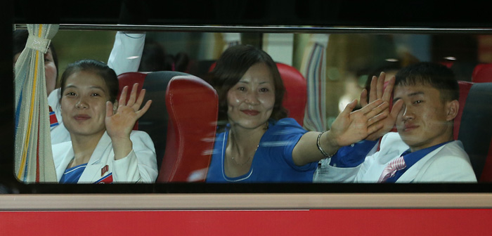 North Korean athletes on the bus wave to supporters who showed up at the airport to greet them. (photo: Yonhap News) 