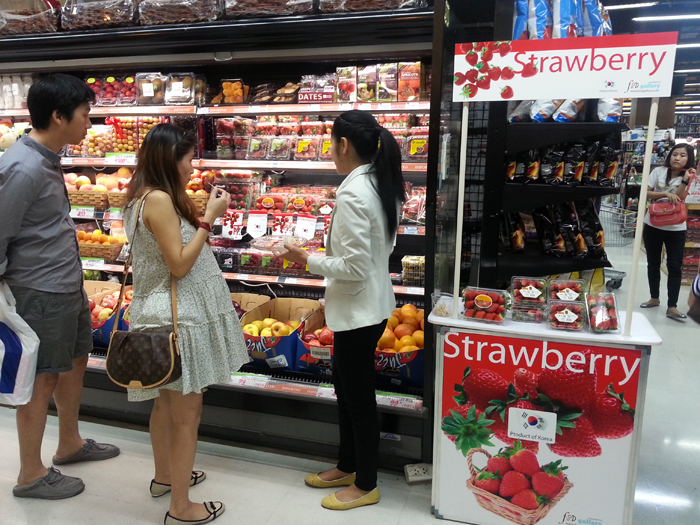Köpare provsmakar koreanska jordgubbar i Thailand. 