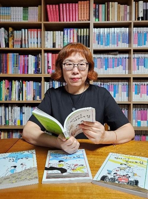 Children's literature author Lee Geum-yi shows several of her published books at the study of her house in Seoul's Jung-gu District.
