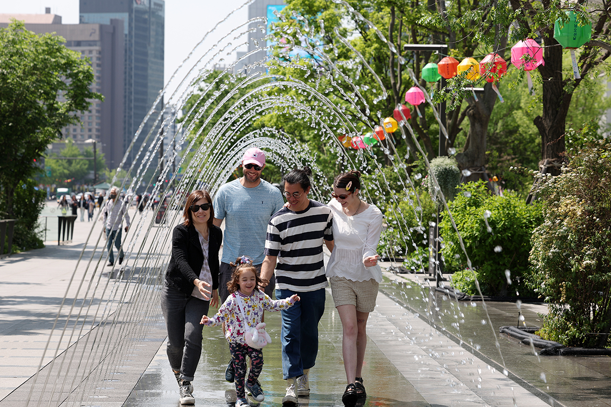 A French family on May 10 happily walks through a water fountain tunnel at Gwanghwamun Square in Seoul's Jongno-gu District, with the daytime temperature reaching a high of 24 degrees Celsius. 