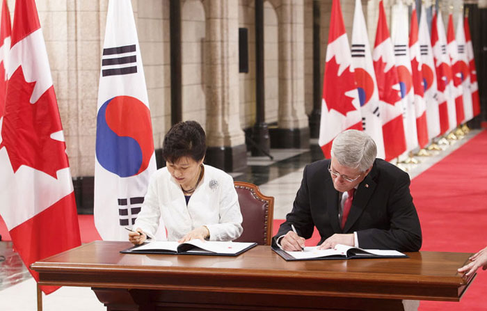 President Park Geun-hye (left) and Canadian Prime Minister Stephen Harper sign the Korea-Canada FTA in the Hall of Honour at Parliament Hill in Ottawa.