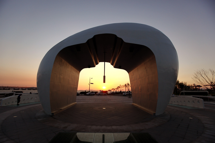 The bell of the Noeuljong sculpture helps frame the sunset's glow.