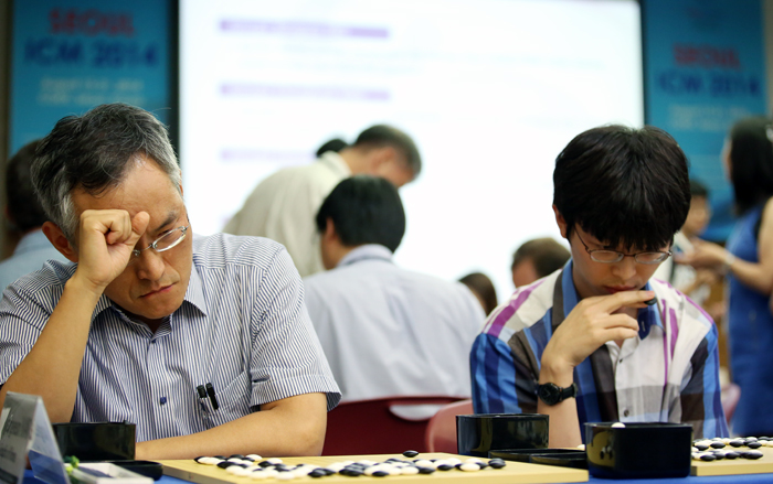 Two participants decide on the next step in a game against Lee Chang-ho.