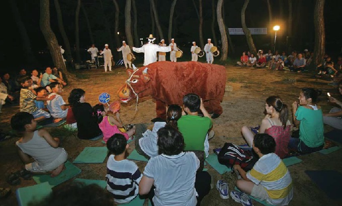 An open-air mask dance performance encourages interactive audience participation. 