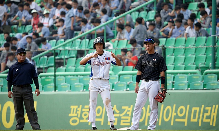 Dashzeveg Munkhbat, the Mongolian batsman, signals to his coach from first base after he proudly gets his country's first hit in the fourth inning.