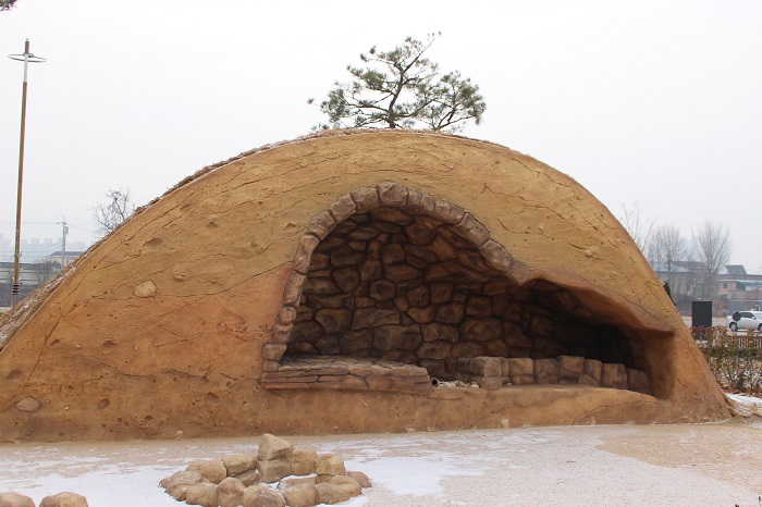 A Buddha carved into a rock face (top) and a Silla tomb (bottom) are part of the outdoor exhibition area at the NRICH.