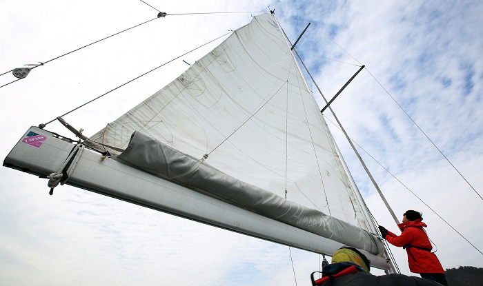 A sailor adjusts the sail to harvest the power of the wind. Renting a sailboat is relatively cheap, enticing more and more tourists to spend their summer holiday here.