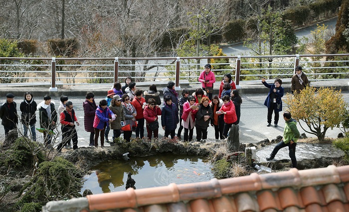 Tourists inspect a pond in front of one of the houses at the House & Garden.