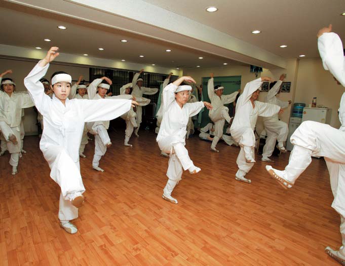 Members of a preservation association practice the basic mask dance steps.