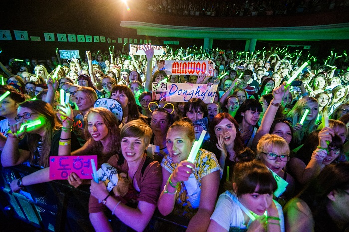 Korean pop music fans in Warsaw yell, cheer and shake their glow sticks to cheer on the dancers and singers.