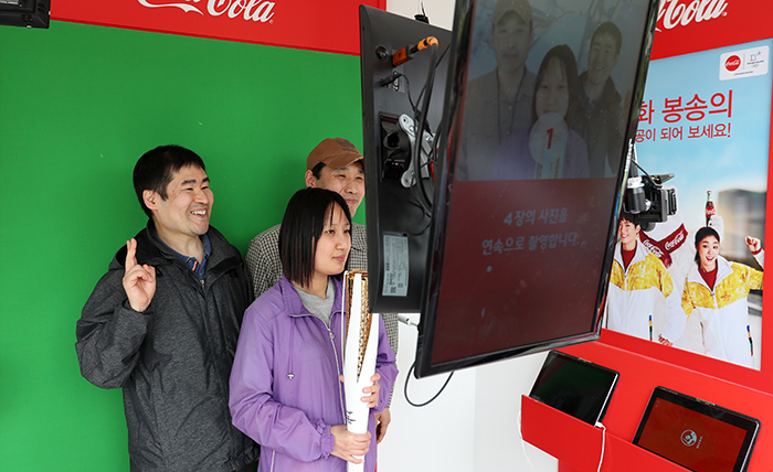 Participants in a hands-on preview for next year’s Winter Olympics and Paralympics hold up an Olympic torch and pose for a photo at the National Folk Museum of Korea, in Seoul on April 25.