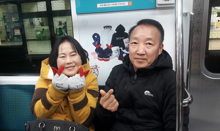Commuters Jeon Min Kyung (left) and Jeong Yeon Chae proudly hold up a pair of 'finger heart' gloves, one of the many official PyeongChang goods available at stores nationwide, on an Olympic-themed subway car in Seoul on Nov. 11. (Kang Gahui)