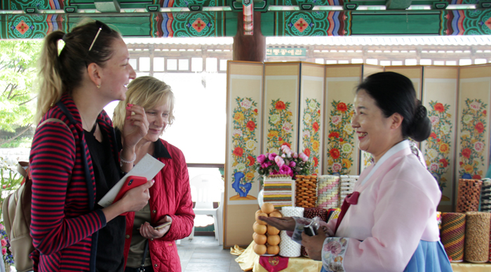 Julia Devochikina (left) from Russia and her mother listen to an explanation about a birthday feast table that was prepared according to traditions in the North Korean city of Gaeseong, at the Namsangol Hanok Village in Jung-gu District, Seoul, on May 11. (Lee Yoonseo)