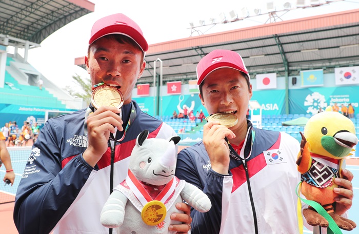 Soft Tennis gold medalist Kim Jinwoong (left) and bronze medalist Kim Donghoon (right) bite their medals after winning the men’s soft tennis singles event, at the Jakabaring Sports City (JSC) Tennis Court in Jakarta on Aug. 29. (Yonhap News)