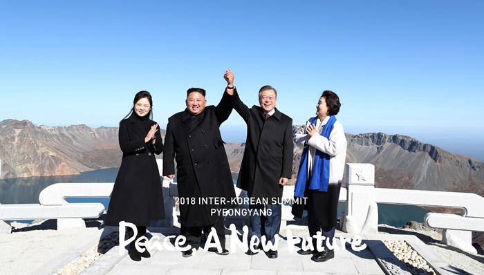President Moon Jae-in (second from right) and North Korea’s Chairman of the State Affairs Commission Kim Jong Un (second from left) hold high each other’s hands atop Janggun Peak of Baekdusan Mountain in North Korea on Sept. 20. (Pyeongyang Press Corps)