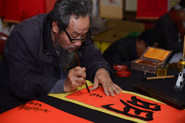  A Vietnamese calligrapher in the long robe ao dai writes lucky words on red paper. (Cao Thi Huong) 