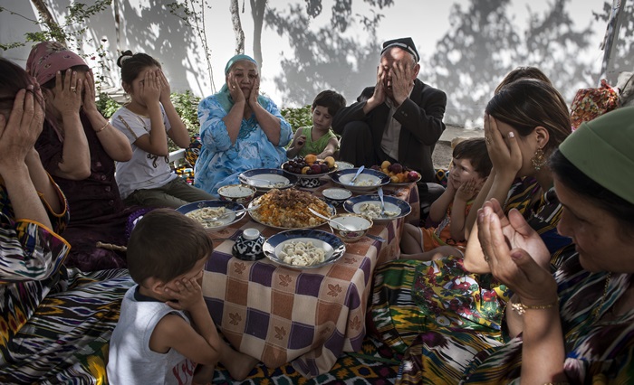 A family in Uzbekistan prays after eating a meal. (Sung Nam-hun).