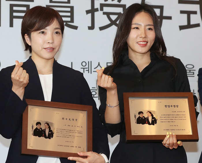 Olympic speed skaters Lee Sang-Hwa and Kodaira Nao on April 7 pose for the camera holding their plaques after receiving the inaugural Korea-Japan Friendship Award in a ceremony at the Westin Chosun Hotel Seoul. (Yonhap News)