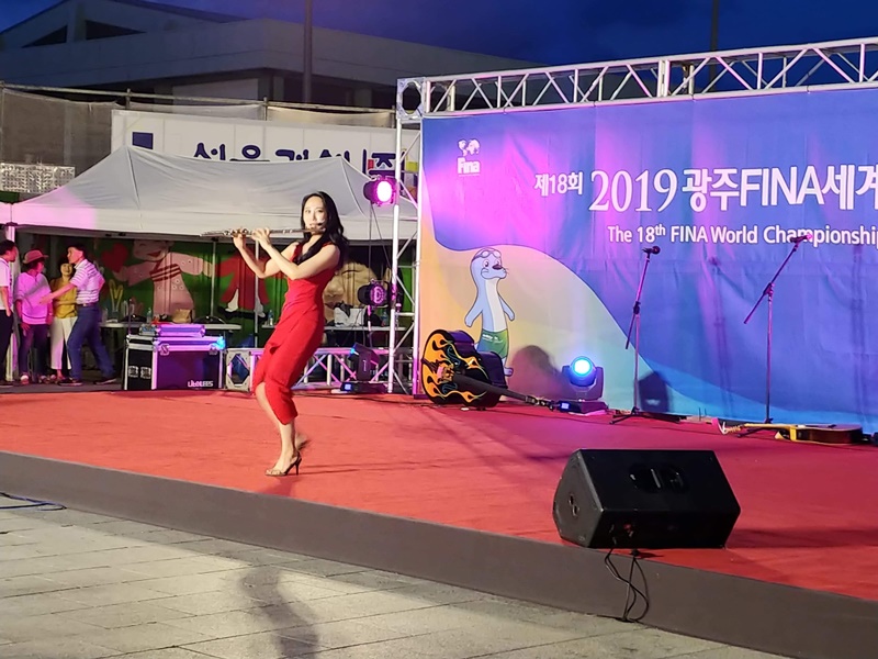 A performer plays the flute in an outdoor concert.