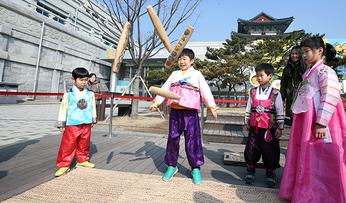  A child throws the <i>yut</i> sticks as he and his family play the game of <i>yut</i> against another family, in front of the National Folk Museum of Korea on Lunar New Year's Day, Seollal, February 19, 2015. 