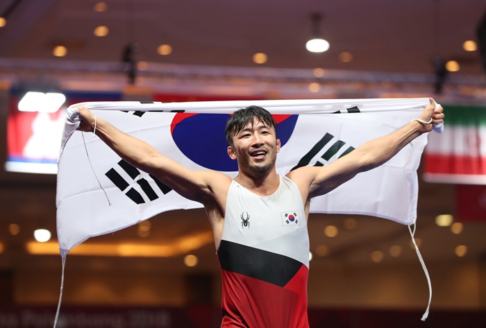 Wrestler Ryu Hansu holds up the Taegeukgi national flag after winning the gold medal in the men’s Greco-Roman 67 kg finals at the Jakarta Convention Center (JCC) in the Indonesian capital on Aug. 21 (Yonhap News)