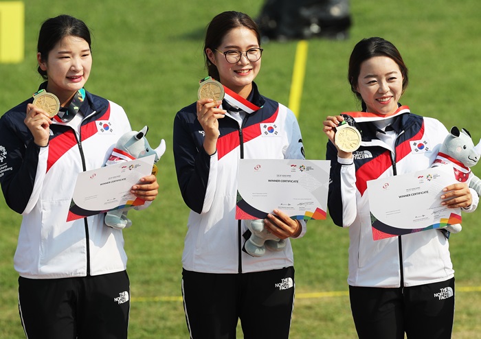 Archery gold medalists Kang Chaeyoung, Lee Eungyeong and Chang Hyejin (from left) hold up their gold medals and post for a commemorative photo during the awards ceremony for the Recurve Women’s Team at the Gelora Bung Karno Stadium in Jakarta on Aug. 27. (Yonhap News)