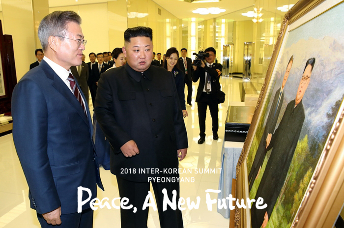 President Moon Jae-in (left) and his North Korean counterpart Chairman Kim Jong Un look at the picture of the two Korean leaders from their second summit in May, which was given as a gift from North Korea’s first couple prior to their welcome dinner at the Mokrangwan state guesthouse in Pyeongyang on Sept. 18. (Pyeongyang Press Corps)