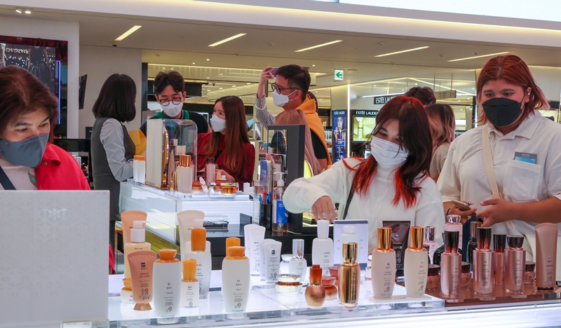 Foreign travelers entering the country from June 1 through international airports on Jeju Island and in Yangyang-gun County, Gangwon-do Province, will not need an entry visa if they observe quarantine guidelines. Shown here on are tourists from Thailand on April 15 viewing products at the main Shinsegae Department Store in the Myeongdong neighborhood of Seoul's Jung-gu District. (Yonhap News)