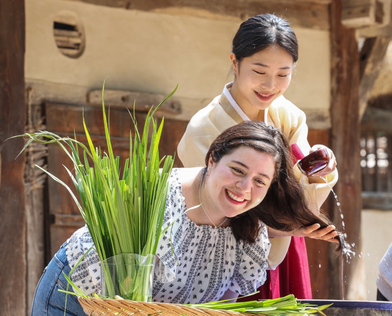 A woman on June 2, the day before Dano, one of Korea's three main traditional holidays that falls on May 5 in the lunar calendar, has her hair washed in water mixed with leaves of the herb changpo (sweet iris) at the National Folk Museum of Korea. 