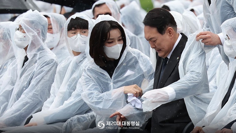 First lady Kim Keon Hee on the morning of June 6 wipes rain off President Yoon Suk Yeol's clothes at a ceremony to mark the 67th Memorial Day at Seoul National Cemetery in the capital's Dongjak-gu District. (Office of the 20th President)