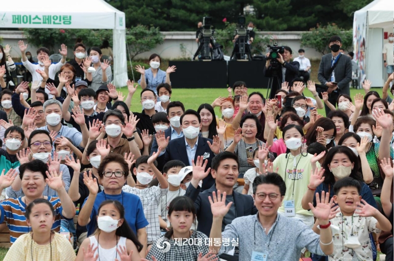 President Yoon Suk Yeol (center in the third row) on June 19 poses for photos with neighbors he invited from Yongsan-gu District of Seoul to a housewarming party at the grass garden in front of the presidential office building in the capital. (Office of the 20th President)