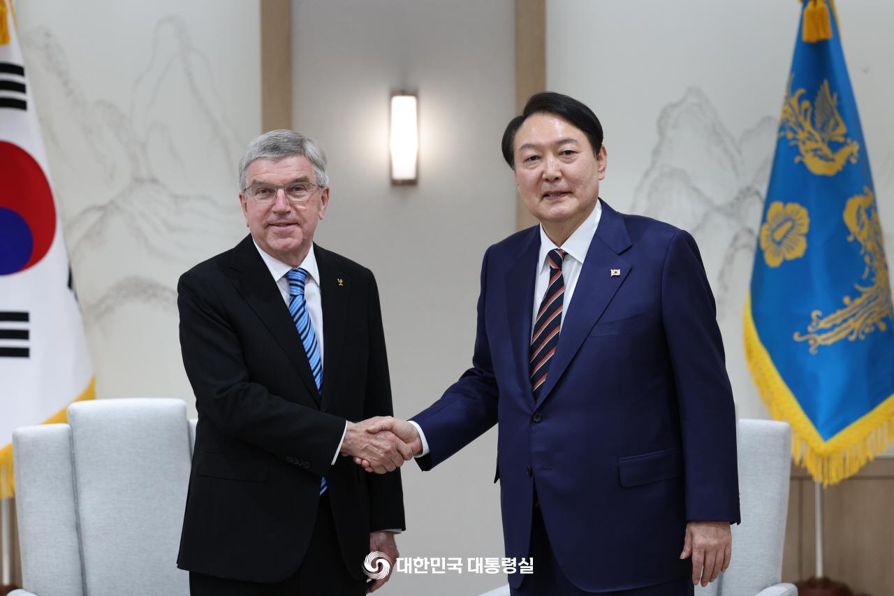 President Yoon Suk Yeol (right) on Oct. 17 shakes hands with International Olympic Committee President Thomas Bach at the presidential office in Seoul's Yongsan-gu District before the dinner. .