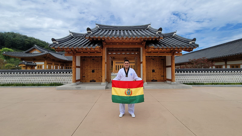 Diego Jaldin holding the Bolivian flag at a turistic spot in Korea. 