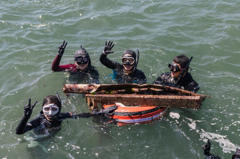 Participants in the (Jeju E-Run Trip) on June 2 pose for a group photo while holding scrap metal they fished out of the sea at Cheonjin Port in the township of Udo-myeon in Jeju City, Jeju Island. (Jeju Tourism Organization) 