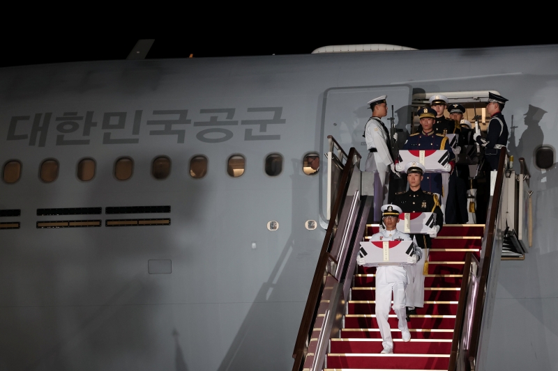 Soldiers unload the remains of soldiers killed in the Korean War prior to a repatriation ceremony. 