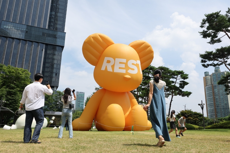 Visitors to Lotte World Tower in Seoul's Songpa-gu District on the afternoon of Aug. 17 take pictures of Bear Balloon at the outdoor lawn plaza.