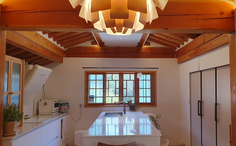 Seoheejae's kitchen forms a harmony of traditional Hanok rafters and windows and modern features like a sink, refrigerator and air conditioner.