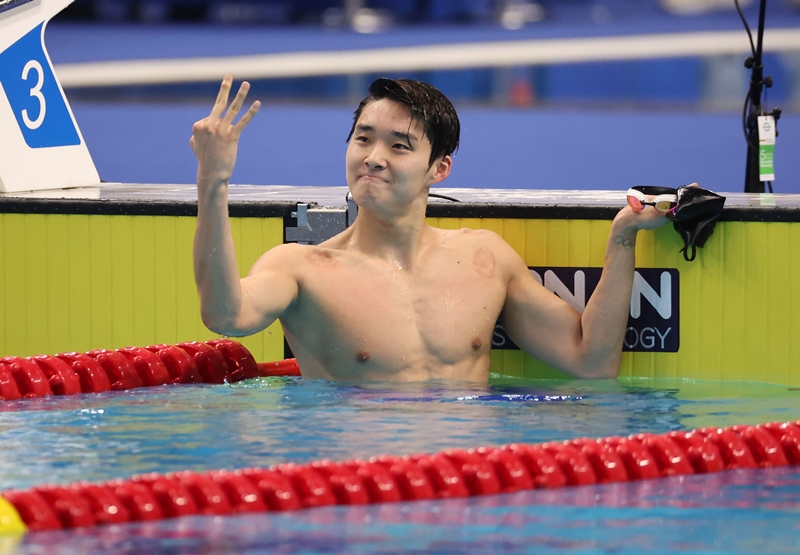 Swimmer Kim Woo-min on Sept. 29 raises three fingers to signify his three gold medals at the Asian Games in Hangzhou, China, after winning the men's 400-meter freestyle at Hangzhou Olympic Sports Centre Aquatic Sports Arena. (Yonhap News) 