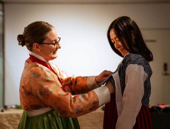 Miranda Day helps a woman wear a Hanbok outfit.