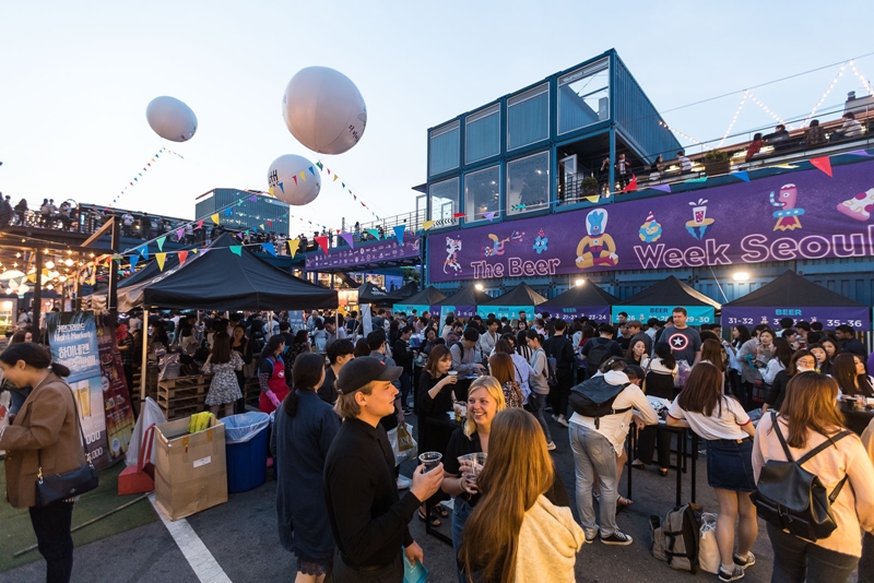 The government on Dec. 8 announced an innovation strategy for tourism exports with the goal of attracting next year 20 million foreign tourists and generating USD 24.5 billion in related revenue. Shown are foreign visitors in June at The Beer Week Seoul held at Common Ground, the first domestic pop-up store built with shipping containers, in the capital's Gwangjin-gu District. (Korea Tourism Organization's official Facebook page)
