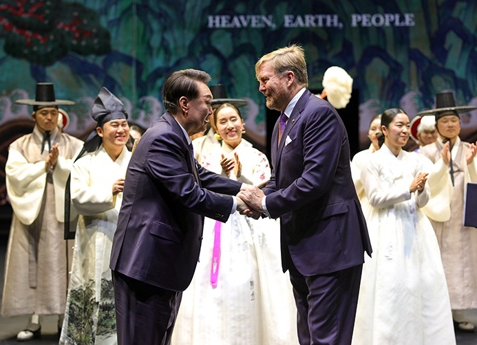 President Yoon Suk Yeol (left) on Dec. 13 at the concert hall AFAS in Amsterdam shakes hands with Dutch King Willem-Alexander on the stage of the performance 