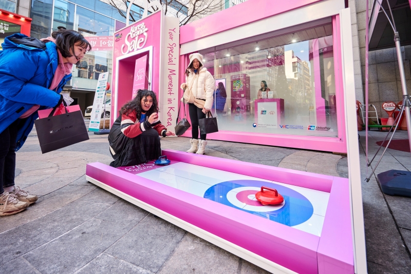 Foreign tourists on Jan. 11 play a mini-curling game at a welcome center within the shopping district of Myeong-dong in Seoul's Jung-gu District in an event to mark the opening of the Korea Grand Sale 2024. (Visit Korea Committee's official Facebook page) 