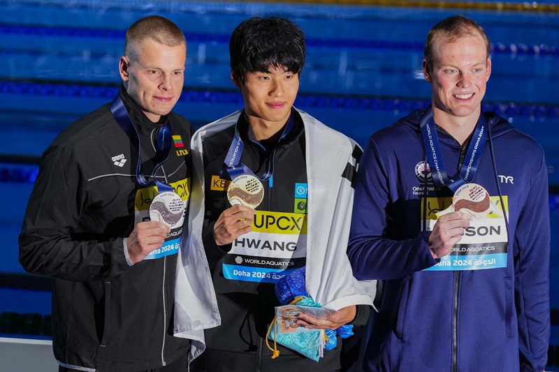 National swimmer Hwang Sun-woo (center) on Feb. 13 at the Aspire Dome in Qatar celebrates with silver medalist Danas Rapsys (left) of Lithuania and bronze medalist Luke Hobson of the U.S. at the medals ceremony for the men's 200-m freestyle at the World Aquatics Championships. (Yonhap News)