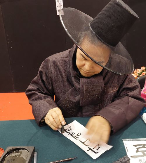 A Korean man from the Coreare Association writes my name 