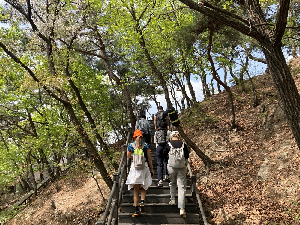 Participants in this year's first tour run by the Bugaksan Mountain branch of Seoul Hiking Tourism Center on April 12 go up stairs on Bugaksan. (Charles Audouin)