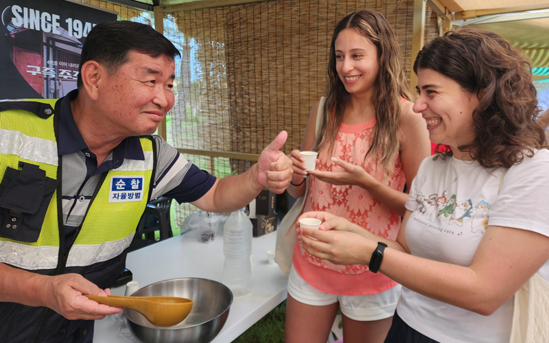 Viviana Souza from Brazil (right) and her Bolivian friend Maria Fernanda Paniagua (middle) on July 27 taste peach makgeolli at the drink booth. On the flavor, Souza said, 