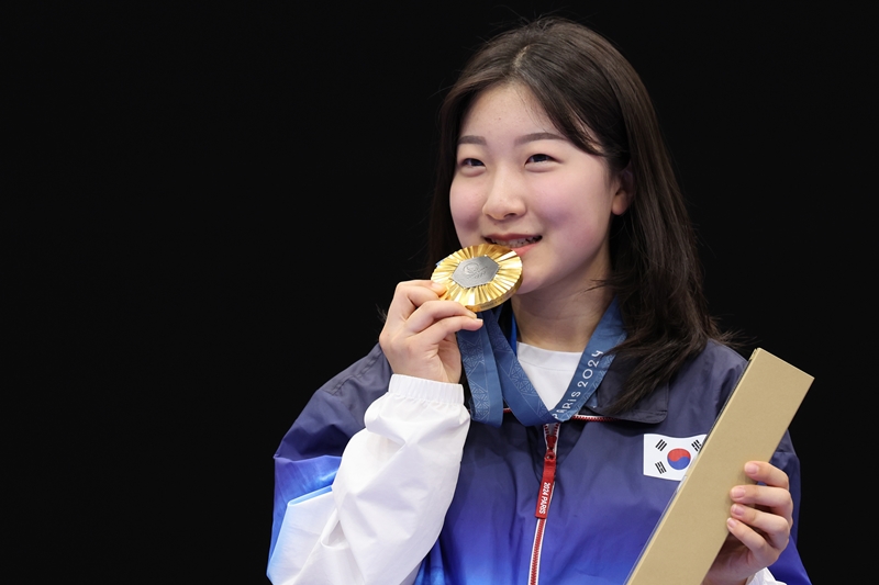 Ban Hyojin on July 29 moves to bite her gold medal in the women's 10 m air rifle at the awards ceremony held at Chateauroux Shooting Centre in Paris.