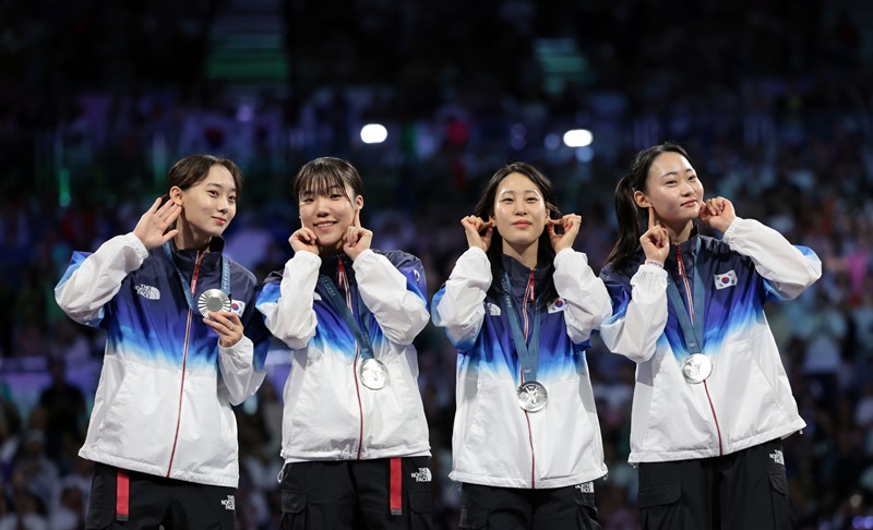 The silver medal-winning national women's fencing team  of (from left) Yoon Ji-soo, Jeon Ha-young, Jeon Eun-hye and Choi Se-bin on Aug. 3 perfroms an earring gesture at the medals ceremony of the Paris Summer Olympics held at the Grand Palais. .